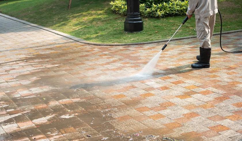 Pressure washing a paved area, dirt lifting away from the pavers