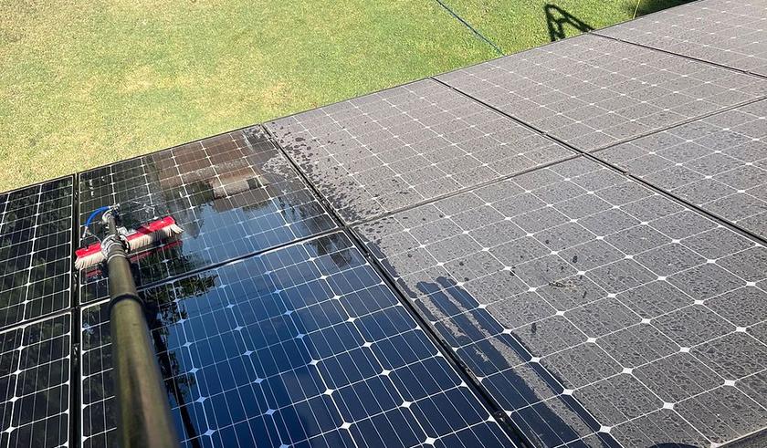Water-fed brush cleaning solar panels, cleaned panels beside dusty ones